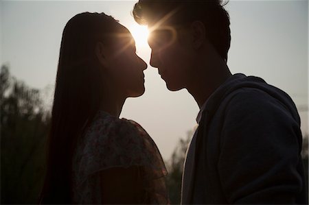 simsearch:614-06896801,k - Silhouette of young couple very close to each other, sunbeam and lens flare Stock Photo - Premium Royalty-Free, Code: 6116-07235963