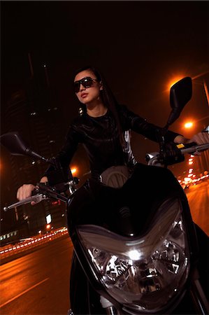 simsearch:6116-07236256,k - Beautiful young woman riding motorcycle in sunglasses through the city streets at night Stock Photo - Premium Royalty-Free, Code: 6116-07235909