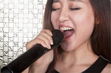 singers - Close-up of young woman singing into a microphone at karaoke Foto de stock - Sin royalties Premium, Código: 6116-07236059