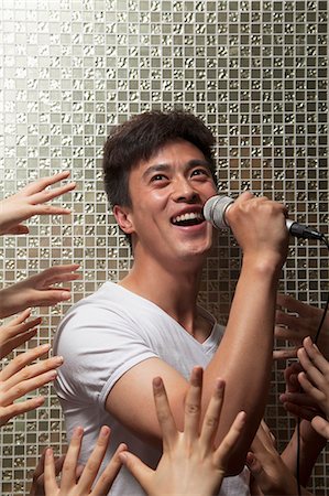 simsearch:6116-07236256,k - Young man singing into a microphone with lots of hands reaching for him Stock Photo - Premium Royalty-Free, Code: 6116-07236061