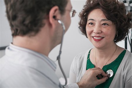 Doctor checking heartbeat of a patient with a stethoscope Stock Photo - Premium Royalty-Free, Code: 6116-07236073