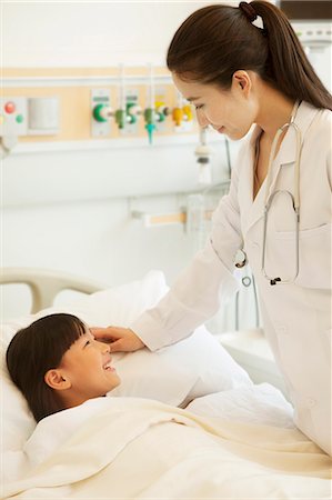 Female doctor talking to girl patient lying down on a hospital bed Stock Photo - Premium Royalty-Free, Code: 6116-07236088