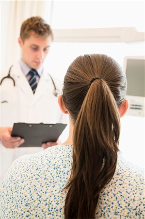 pony tail - Doctor discussing medical chart with a patient sitting on a hospital bed Stock Photo - Premium Royalty-Free, Code: 6116-07236094