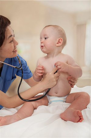 Smiling doctor checking a baby's heart beat with a stethoscope  in the doctors office Photographie de stock - Premium Libres de Droits, Code: 6116-07236023