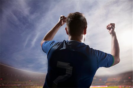 sports and winning - Soccer player with arms raised cheering, stadium with sky and clouds Stock Photo - Premium Royalty-Free, Code: 6116-07236125
