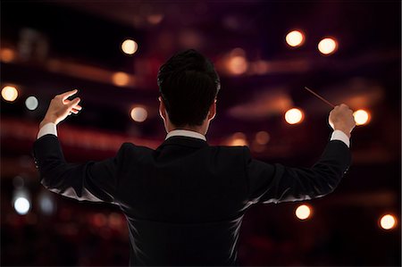 Young conductor with baton raised at a performance, rear view Stock Photo - Premium Royalty-Free, Code: 6116-07236209