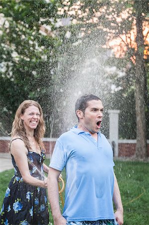 Couple playing with a garden hose and spraying each other outside in the garden, man has a shocked look Photographie de stock - Premium Libres de Droits, Code: 6116-07236235