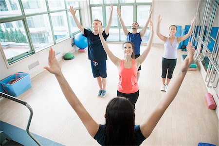 Young people with hands in the air in a yoga class Stock Photo - Premium Royalty-Free, Code: 6116-07236348