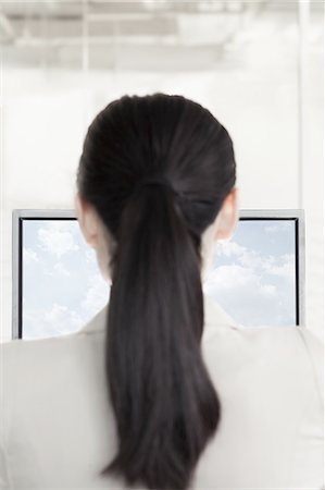 simsearch:6116-07084811,k - Businesswoman sitting in front of a computer with clouds and sky on the monitor Stock Photo - Premium Royalty-Free, Code: 6116-07236467