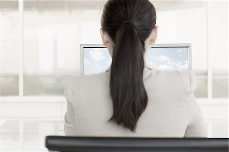 simsearch:6116-07084811,k - Businesswoman sitting in front of a computer with clouds and sky on the monitor Stock Photo - Premium Royalty-Free, Code: 6116-07236466