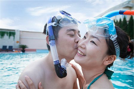 simsearch:6116-07236315,k - Smiling couple kissing on the cheek wearing snorkeling gear in the pool Foto de stock - Sin royalties Premium, Código: 6116-07236423