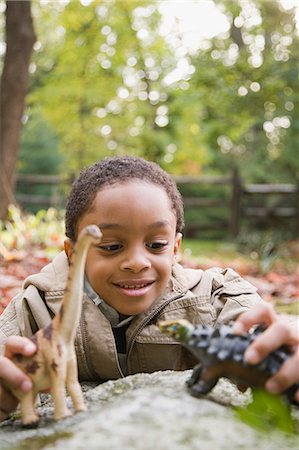 Boy playing with toy dinosaurs Photographie de stock - Premium Libres de Droits, Code: 6116-08945542