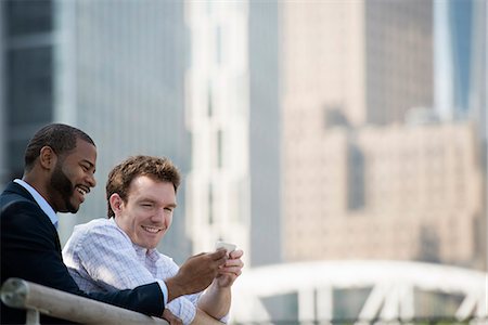 Summer. Two Men Looking At A Smart Phone, Texting And Photo Messaging. Stock Photo - Premium Royalty-Free, Code: 6118-07121852