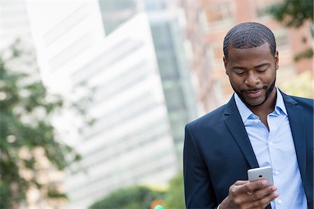 summer text message - Summer. A Man In A Blue Jacket And Open Collared Shirt Using A Smart Phone. Stock Photo - Premium Royalty-Free, Code: 6118-07121855
