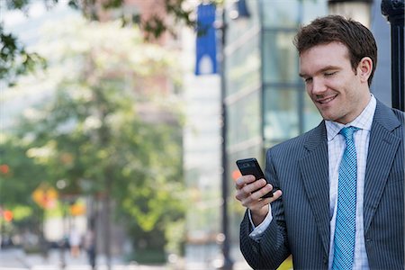 simsearch:6118-07121866,k - Summer. A Young Man In A Grey Suit And Blue Tie. Using A Smart Phone. Stock Photo - Premium Royalty-Free, Code: 6118-07121861
