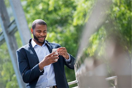 simsearch:6118-07121866,k - Summer. A Man In A Blue Jacket And Open Necked Shirt. Using A Smart Phone. Stock Photo - Premium Royalty-Free, Code: 6118-07121873