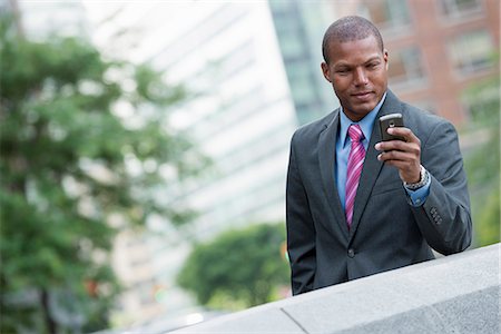 simsearch:6118-07121993,k - A Young Man In A Business Suit With A Blue Shirt And Red Tie. On A New York City Street. Using A Smart Phone. Stock Photo - Premium Royalty-Free, Code: 6118-07121945