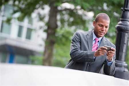 simsearch:6118-08243810,k - A Young Man In A Business Suit With A Blue Shirt And Red Tie. On A New York City Street. Using A Smart Phone. Stock Photo - Premium Royalty-Free, Code: 6118-07121946