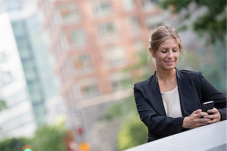 simsearch:6118-08243810,k - A Young Blonde Businesswoman On A New York City Street. Wearing A Black Jacket. Using A Smart Phone. Stock Photo - Premium Royalty-Free, Code: 6118-07121949