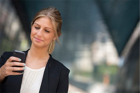 simsearch:6118-08243810,k - A Young Blonde Businesswoman On A New York City Street. Wearing A Black Jacket. Using A Smart Phone. Stock Photo - Premium Royalty-Free, Code: 6118-07121967