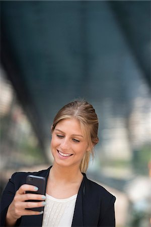 simsearch:6118-07121993,k - A Young Blonde Businesswoman On A New York City Street. Wearing A Black Jacket. Using A Smart Phone. Stock Photo - Premium Royalty-Free, Code: 6118-07121968