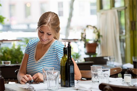 simsearch:6118-08243810,k - A Woman In A Striped Tee Shirt Sitting At A Table After A Meal, Checking Her Smart Phone. Stock Photo - Premium Royalty-Free, Code: 6118-07121979
