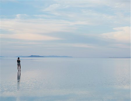 saltflat - A Woman Standing On The Flooded Bonneville Salt Flats At Dusk. Reflections In The Shallow Water. Foto de stock - Sin royalties Premium, Código: 6118-07122087