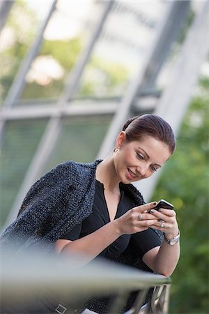 simsearch:6118-07121993,k - Business People. A Woman In A Grey Jacket With Her Hair Up, Using A Phone. Stock Photo - Premium Royalty-Free, Code: 6118-07122039