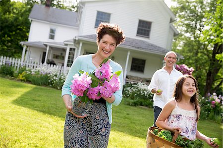 farmhouse - Family Party. Parents And Children Walking Across The Lawn Carrying Flowers, Fresh Picked Vegetables And Fruits. Preparing For A Party. Stock Photo - Premium Royalty-Free, Code: 6118-07122194