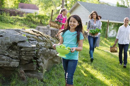 simsearch:6118-07122193,k - Organic Farm. Summer Party. A Family Carrying Baskets And Bowls Of Food Across The Grass. Foto de stock - Sin royalties Premium, Código: 6118-07122135