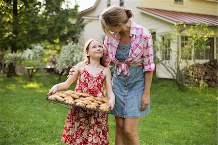 simsearch:6122-07698008,k - Baking Homemade Cookies. A Young Girl Holding A Tray Of Fresh Baked Cookies, And An Adult Woman Leaning Down To Praise Her. Stock Photo - Premium Royalty-Free, Code: 6118-07122244