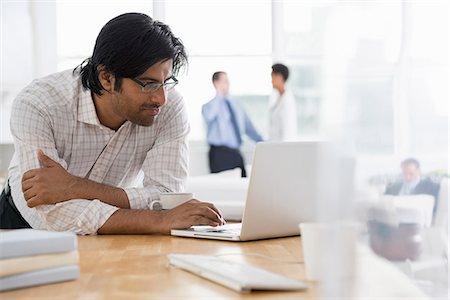 Office. A Young Man Using A Laptop Computer On A Desk. Stock Photo - Premium Royalty-Free, Code: 6118-07122399