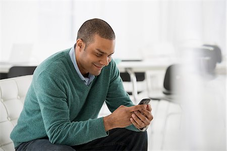 Business. A Man Seated, Checking His Smart Phone For Messages And Texting. Stock Photo - Premium Royalty-Free, Code: 6118-07122544
