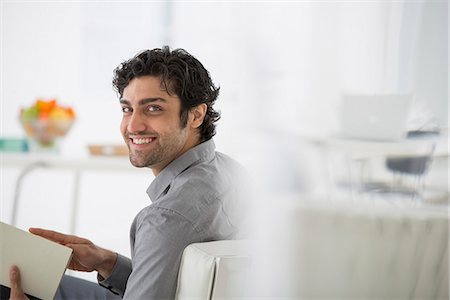 Business. A Man Sitting Holding A Book In His Hands. Turning Around And Smiling. Fotografie stock - Premium Royalty-Free, Codice: 6118-07122555