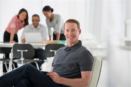 simsearch:6118-07351367,k - Business. Four People, One Man Sitting On A Soft Chair, And Three People Working Together On A Laptop. Photographie de stock - Premium Libres de Droits, Code: 6118-07122569