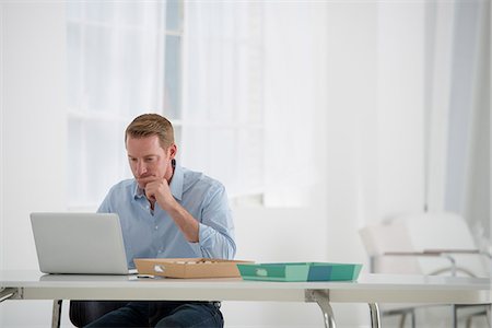 person sits on the chair and front view - Business. A Man Sitting At A Desk Using A Laptop. Stock Photo - Premium Royalty-Free, Code: 6118-07122584