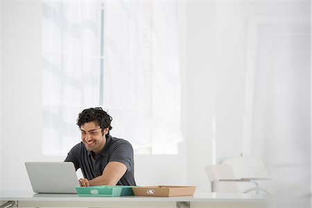 person on laptop - Business. A Man Sitting At A Desk Using A Laptop. Stock Photo - Premium Royalty-Free, Code: 6118-07122594