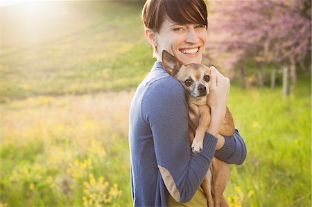field of flowers america - A Young Woman In A Grassy Field In Spring. Holding A Small Chihuahua Dog In Her Arms. A Pet. Stock Photo - Premium Royalty-Free, Code: 6118-07122751