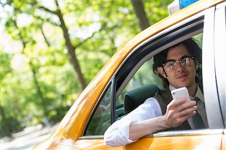 A Young Man In The Back Seat Of A Yellow Cab, Looking At His Smart Phone. Photographie de stock - Premium Libres de Droits, Code: 6118-07122774