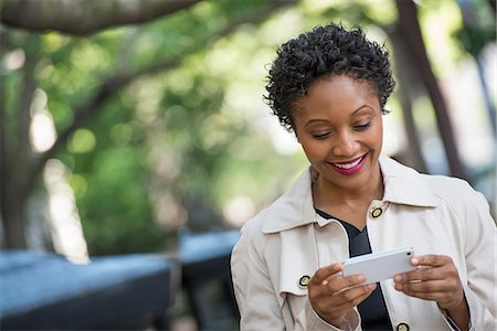 City. A Woman Outdoors In The Park, Checking Her Smart Phone. Stock Photo - Premium Royalty-Free, Code: 6118-07122791
