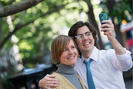 simsearch:6118-07440408,k - City. Two People, A Man And Woman Outdoors, Side By Side Posing For A Photograph Using His Smart Phone. Stock Photo - Premium Royalty-Free, Code: 6118-07122799