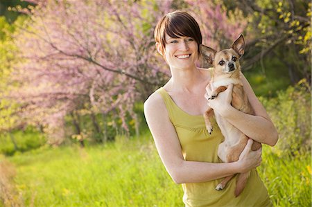 simsearch:6118-07122740,k - Young Woman In Grassy Field In Spring Holding A Dog Photographie de stock - Premium Libres de Droits, Code: 6118-07122739