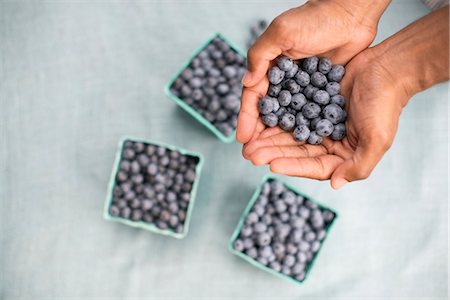 simsearch:6118-07441027,k - Punnets of fresh organic soft fruits. A person holding a handful of blueberries. Photographie de stock - Premium Libres de Droits, Code: 6118-07203012