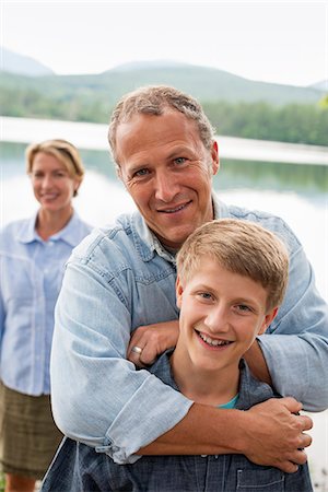 polo shirt - A family outdoors under the trees on a lake shore. Two adults and a young boy. Stock Photo - Premium Royalty-Free, Code: 6118-07203124