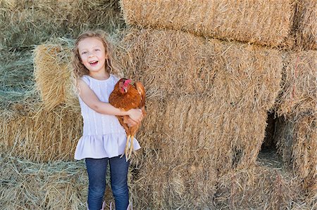simsearch:6118-07354442,k - A young girl standing in a hay barn holding a chicken in her arms. Stock Photo - Premium Royalty-Free, Code: 6118-07203315