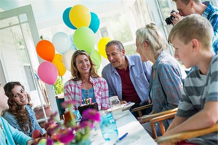 A birthday party in a farmhouse kitchen. A group of adults and children gathered around a chocolate cake. Photographie de stock - Premium Libres de Droits, Code: 6118-07203422