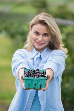 simsearch:6118-07203696,k - Picking blackberry fruits on an organic farm. A woman holding out a full punnet of glossy berries. Stock Photo - Premium Royalty-Free, Code: 6118-07203681