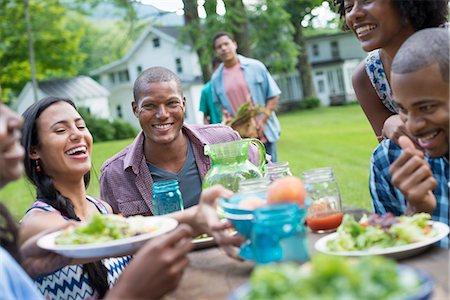 A group of adults and young people at a meal in the garden of a farmhouse. Passing plates and raising glasses. Stock Photo - Premium Royalty-Free, Code: 6118-07203746