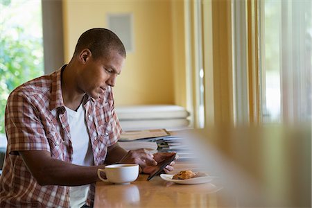 simsearch:6118-07203820,k - A man seated having a cup of coffee, holding a digital tablet. Stock Photo - Premium Royalty-Free, Code: 6118-07203775