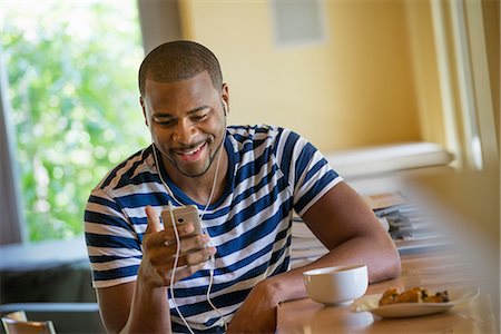 simsearch:6118-07203820,k - A man using a smart phone, or personal music player, wearing headphones. Stock Photo - Premium Royalty-Free, Code: 6118-07203781